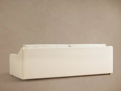 Close-up of the cream Ashby Sofa, showing the textured fabric on the armrest, back cushion, and a throw pillow.