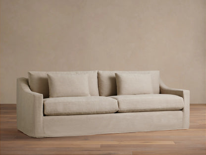 Ashby Slipcovered Sofa in light beige fabric, featuring two seat cushions, two back cushions, and two square throw pillows.