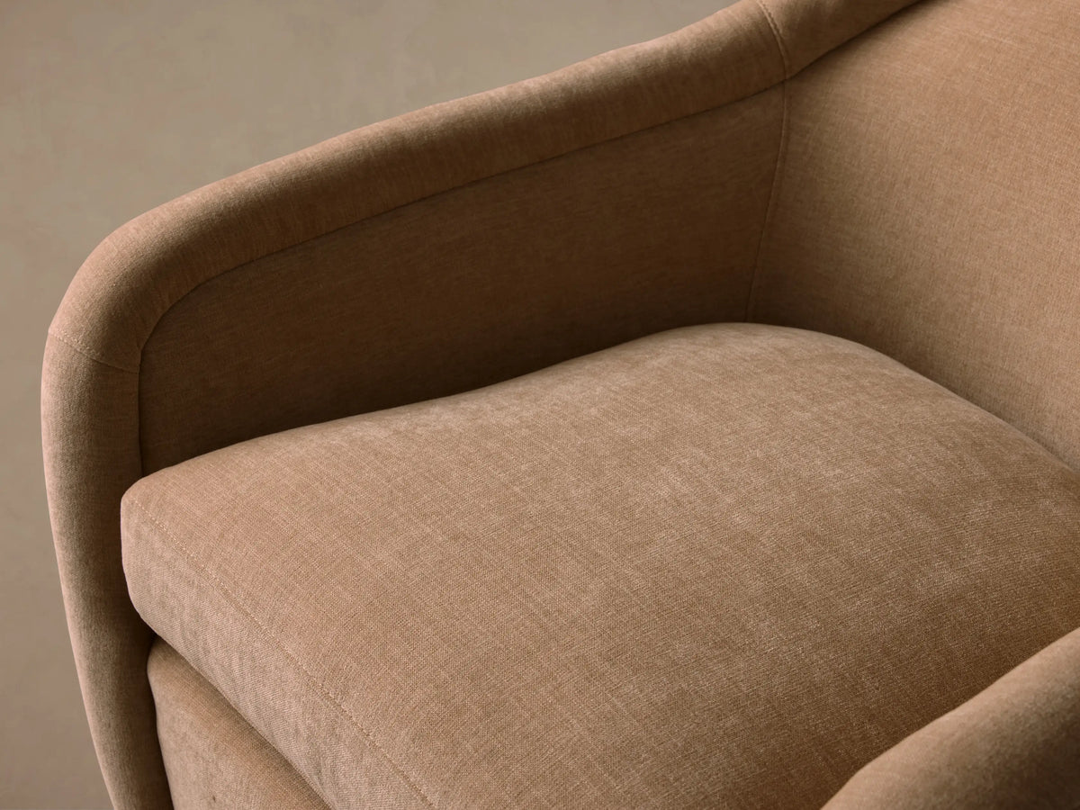 Ashbury Swivel Chair: light beige upholstered chair with rounded back, arms, plump cushion, and dark circular swivel base.