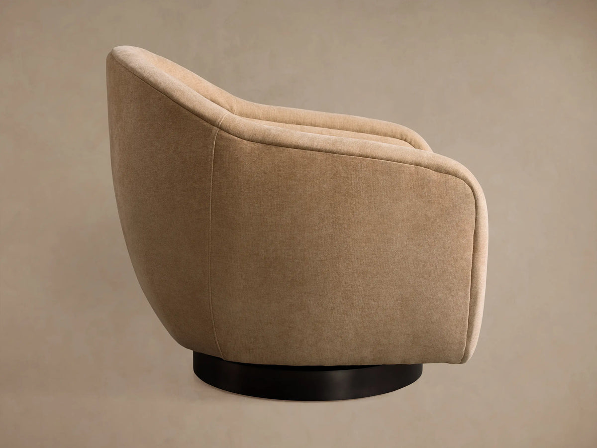 Light beige Ashbury Swivel Chair, angled back view, showcasing its rounded form and black circular base.