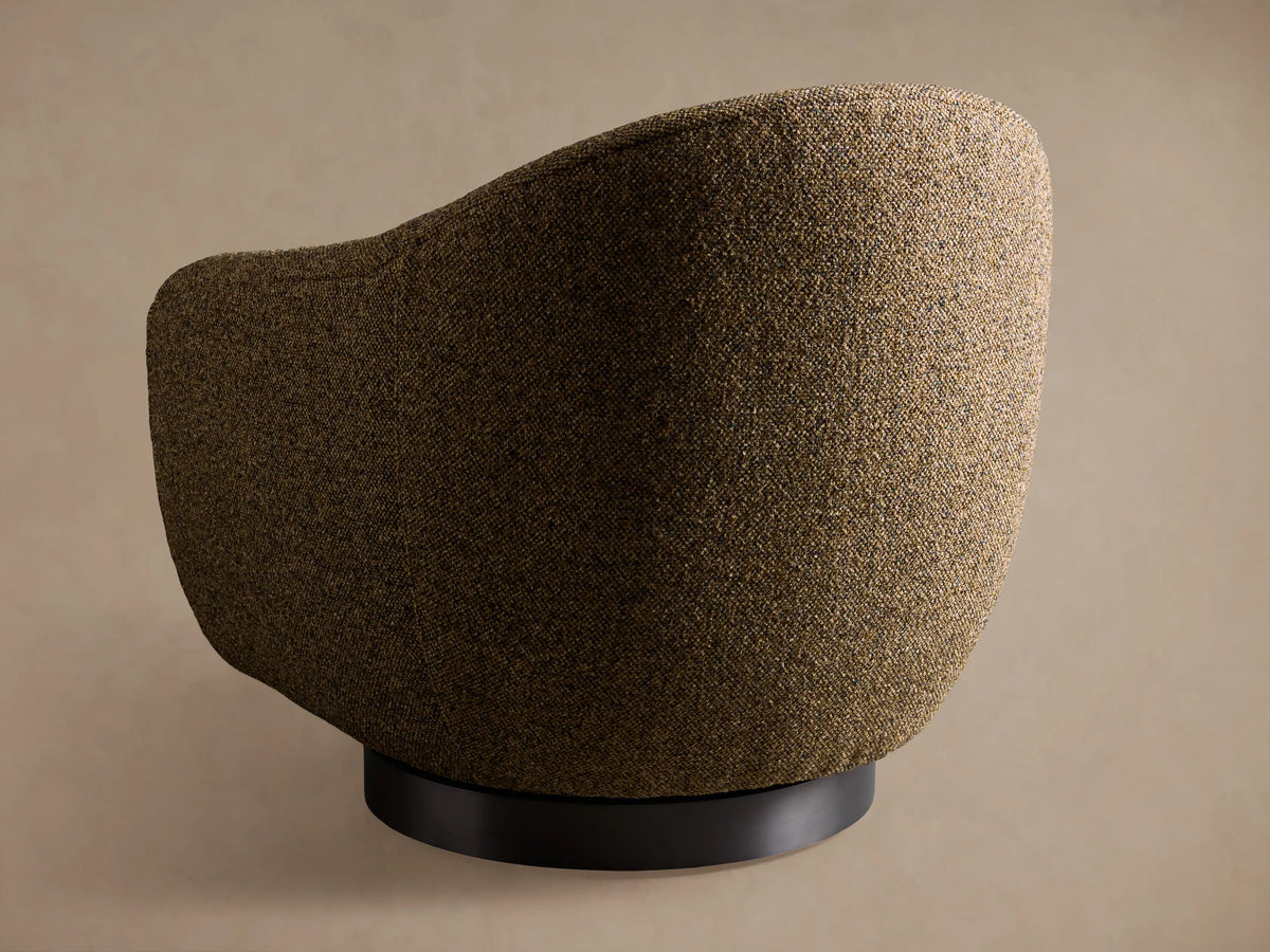Ashbury Swivel Chair close-up. Textured woven fabric in earthy browns, beiges, and subtle dark flecks on cushion and armrest.