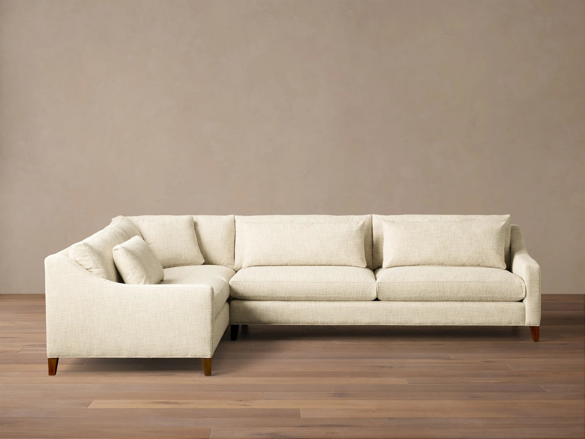 Front view of a cream Ashby Elevated Two-Piece Sectional, featuring a left-hand corner configuration and mocha wooden legs.
