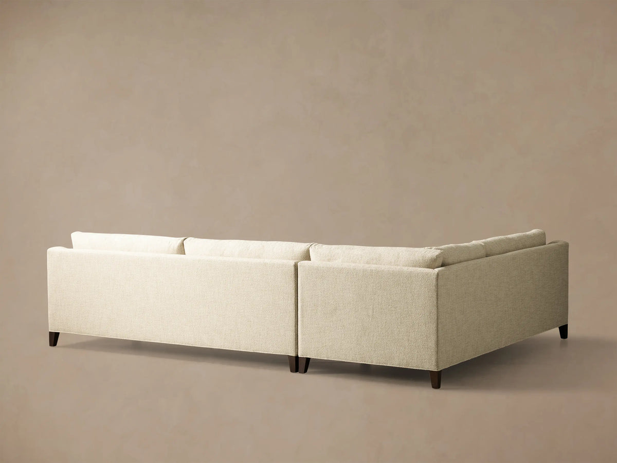 Angled view of a light beige textured Ashby Elevated Two-Piece Sectional with straight armrests and rich mocha-finished elevated legs.