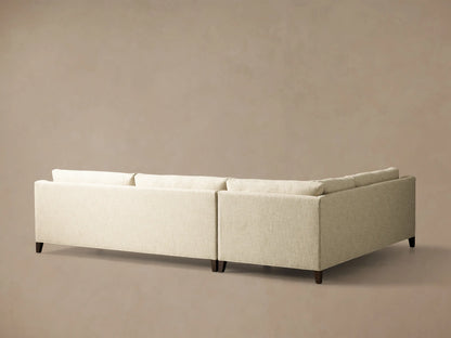 Angled view of a light beige textured Ashby Elevated Two-Piece Sectional with straight armrests and rich mocha-finished elevated legs.