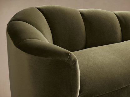 Amira Daybed: luxurious olive green velvet chaise lounge, left-facing with a sculpted, curved back on a wood floor.