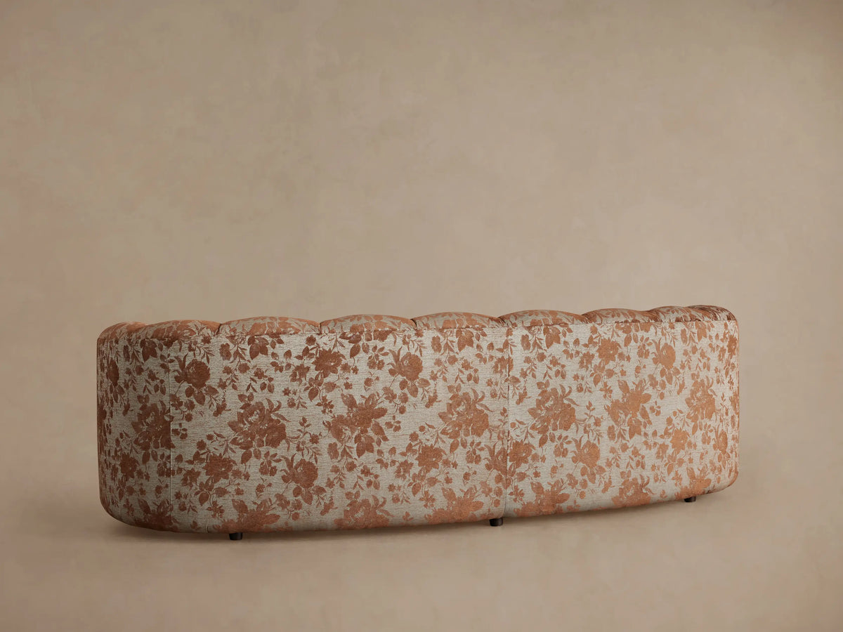 Close-up of Amira Sofa in Cinnamon. Plush solid cinnamon seat cushion beside plump back cushions with a cinnamon floral pattern.