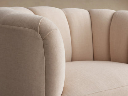 Amira Swivel Chair in blush fabric, featuring a rounded design with plush, tufted backrest and a 360-degree swivel base on a wooden floor.