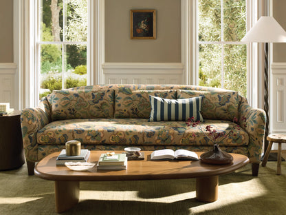 Front view of the Alina Sofa with beige upholstery in a multi-colored floral and paisley pattern, three back cushions, and dark wood legs.