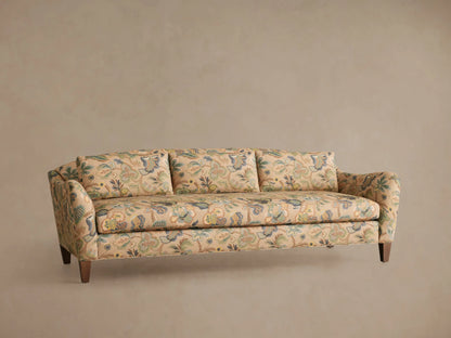 Front view of the Alina Sofa, upholstered in a beige fabric with an intricate blue and green floral pattern, in a living room.