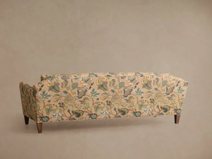 Close-up of the beige fabric on the Alina Sofa, featuring an intricate botanical and chinoiserie pattern in greens, blues, and browns.