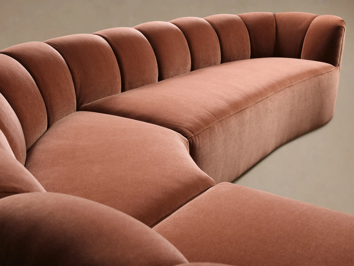 Front view of a terra cotta velvet Amira Three-Piece Corner Sectional with a curved, channel-tufted backrest.