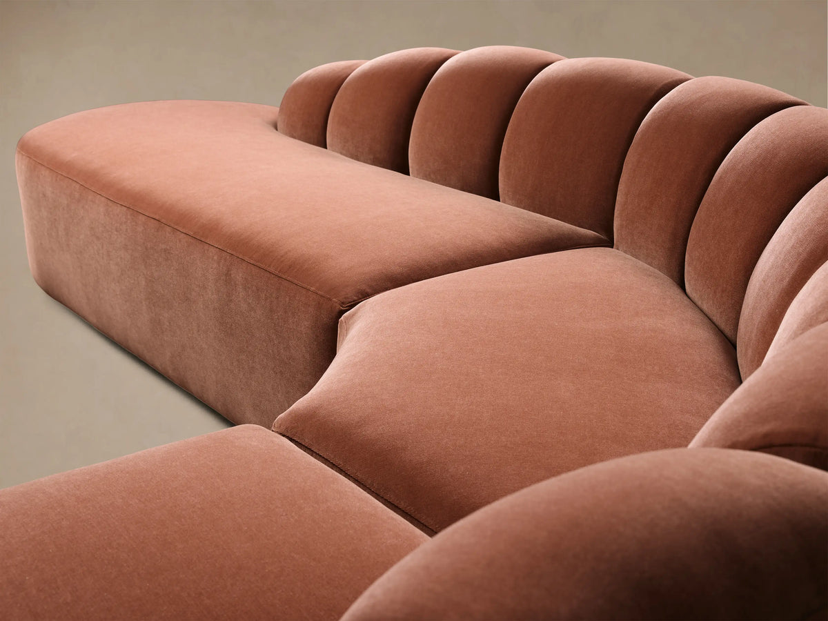 Front view of the terracotta pink Amira Three-Piece Bumper Sectional with a curved design and channel tufted back.