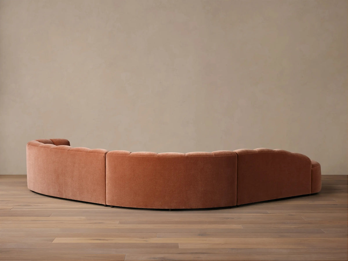 Close-up of a terracotta Amira Three-Piece Bumper Sectional, showing plush upholstered curved backrest cushions.