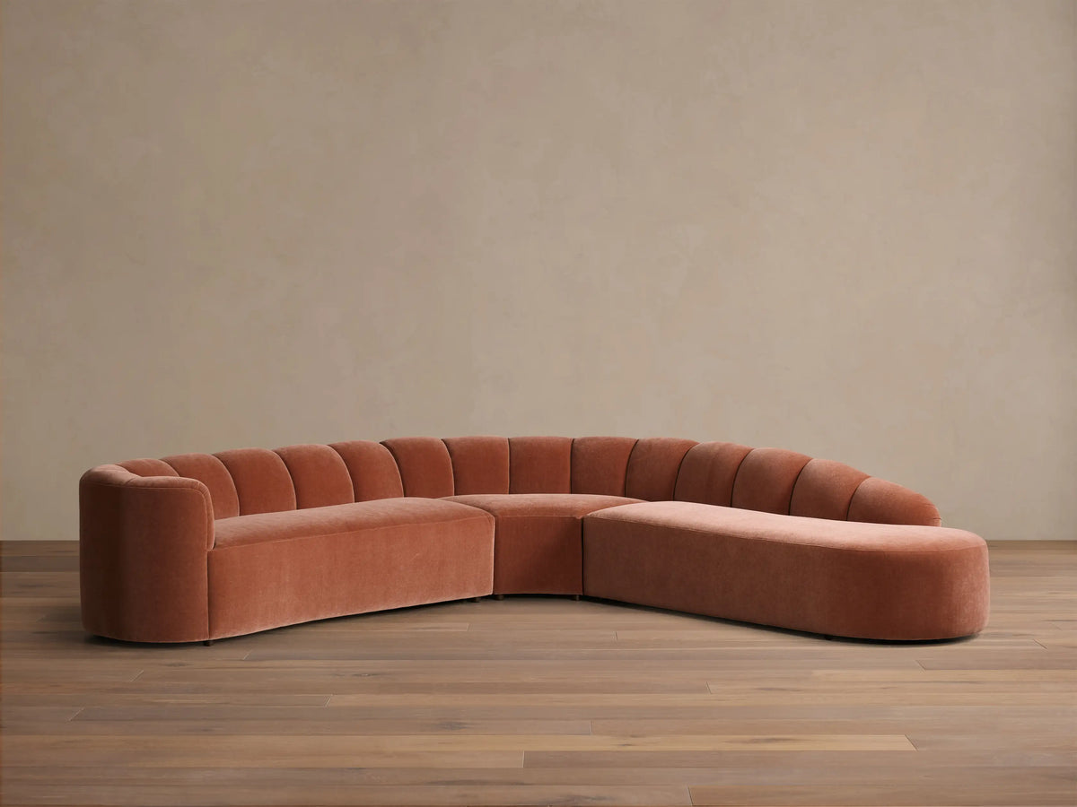 Front view of the terracotta velvet Amira Three-Piece Bumper Sectional with a curved design and channel-tufted back.
