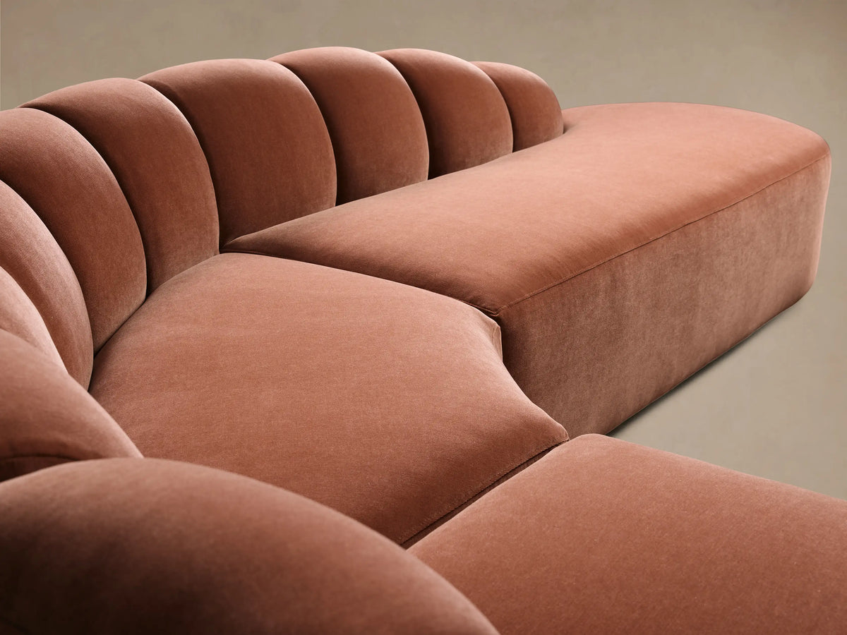 Close-up of the dusty rose Amira Three-Piece Bumper Sectional, highlighting its curved channeled backrest and plush seat.