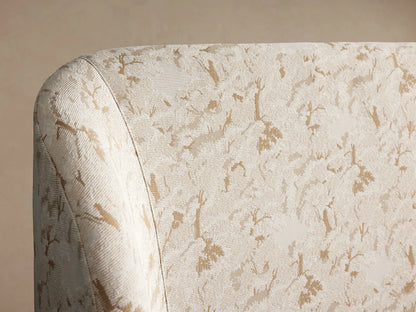 Adalynn Bed's upholstered headboard close-up showing cream fabric with subtle beige floral pattern and soft rounded edge.