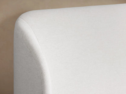 Adalynn Bed's upholstered headboard in light beige fabric with a smooth, curved corner design against a neutral background.