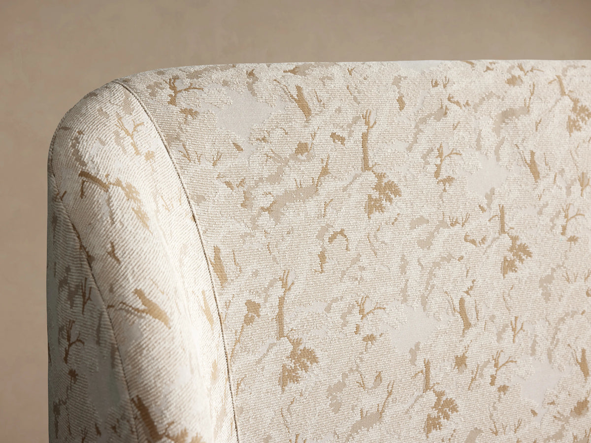 Adalynn Bed headboard with cream and beige floral upholstery pattern, showcasing a curved, padded design against a neutral background.