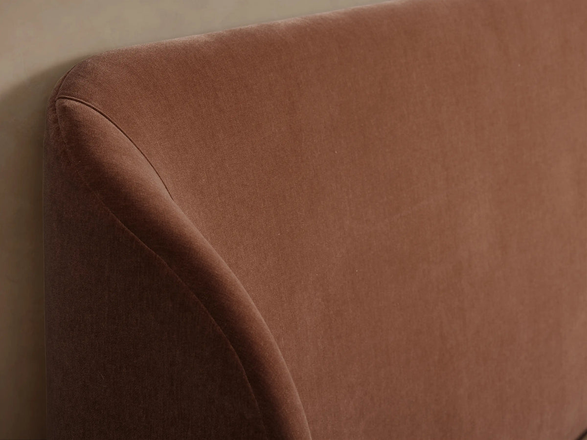 Adalynn Bed with High Footboard upholstered in rust-colored velvet, rounded headboard & footboard, with white bedding.