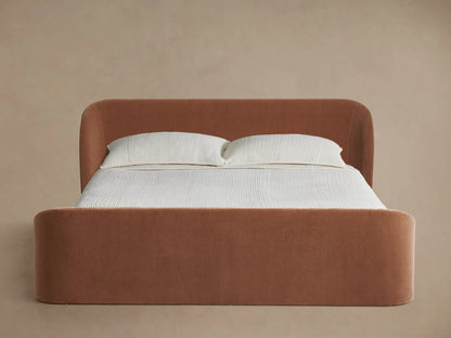 Adalynn Bed: rust-orange upholstered, curved high headboard & footboard, light striped bedding, wood floor.
