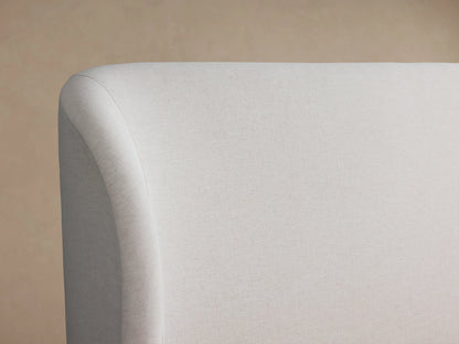 Adalynn Bed's high footboard corner in light fabric, showing smooth, curved upholstery against a neutral background.