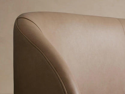 Adalynn Leather Bed showcases a close-up of the upholstered headboard in light taupe leather with curved edges.