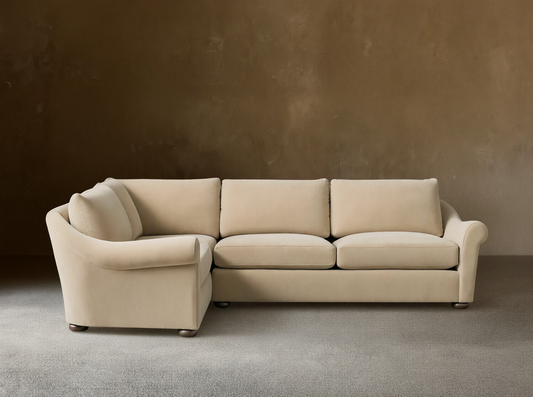 Beige Archwood Two-Piece Sectional on wooden floor, featuring plush cushions, L-shaped design, rolled arms, and dark wooden legs.