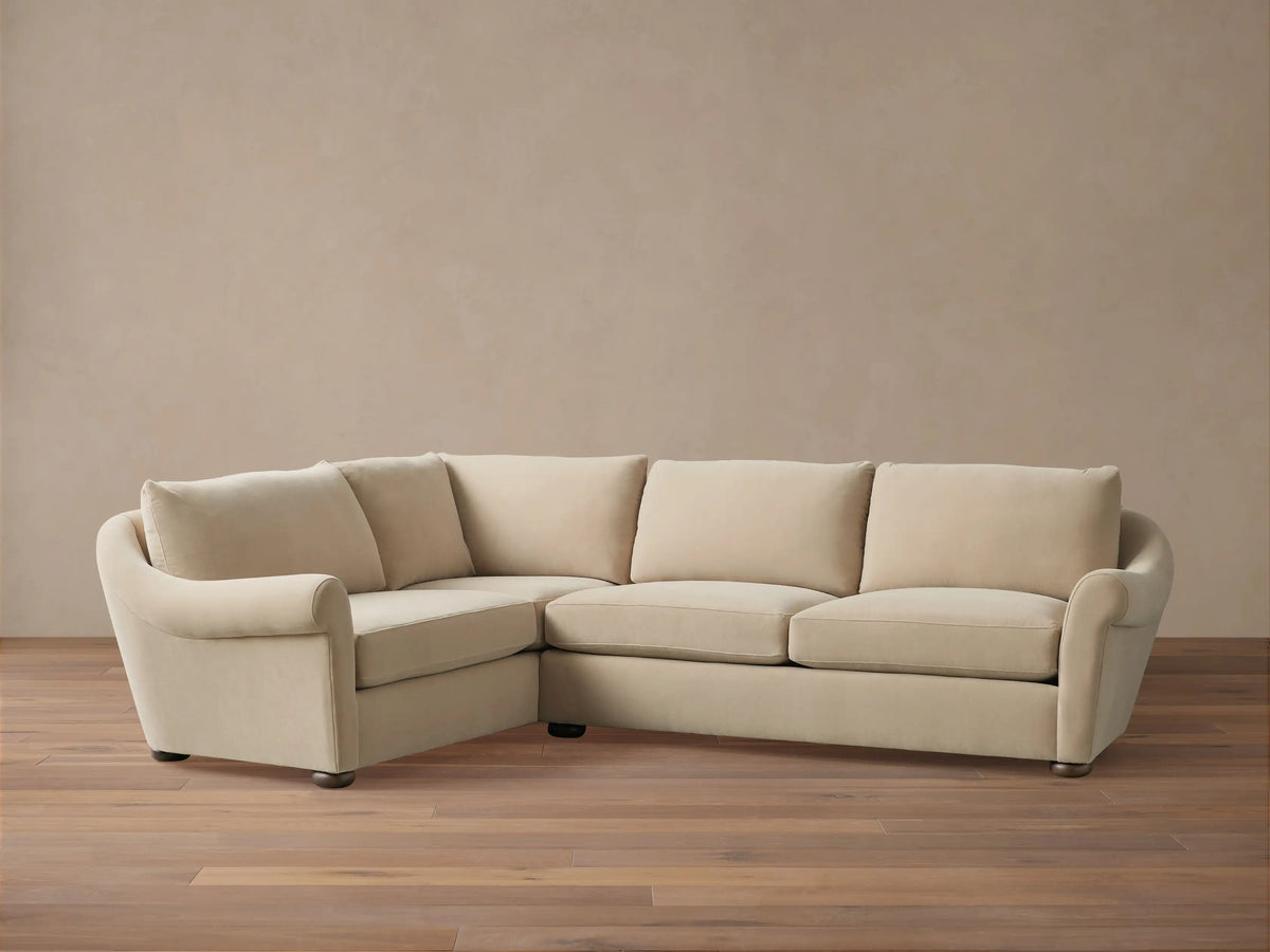Beige Archwood Two-Piece Sectional on wooden floor, featuring plush cushions, L-shaped design, rolled arms, and dark wooden legs.