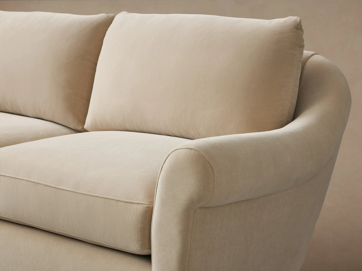 Archwood Two-Piece Sectional in beige fabric shown in a corner configuration with curved arms and plush cushions on a wooden floor.