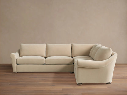 Archwood Three-Piece Corner Sectional in cream fabric, features rounded arms, plush back and seat cushions, on a wood floor.