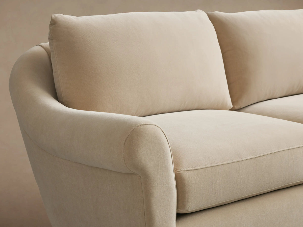 Beige Archwood Three-Piece Corner Sectional on wooden floor, featuring soft fabric, rolled arms, and plush cushions, in L-shape.