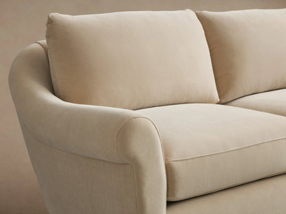 Beige Archwood Three-Piece Corner Sectional on wooden floor, featuring soft fabric, rolled arms, and plush cushions, in L-shape.