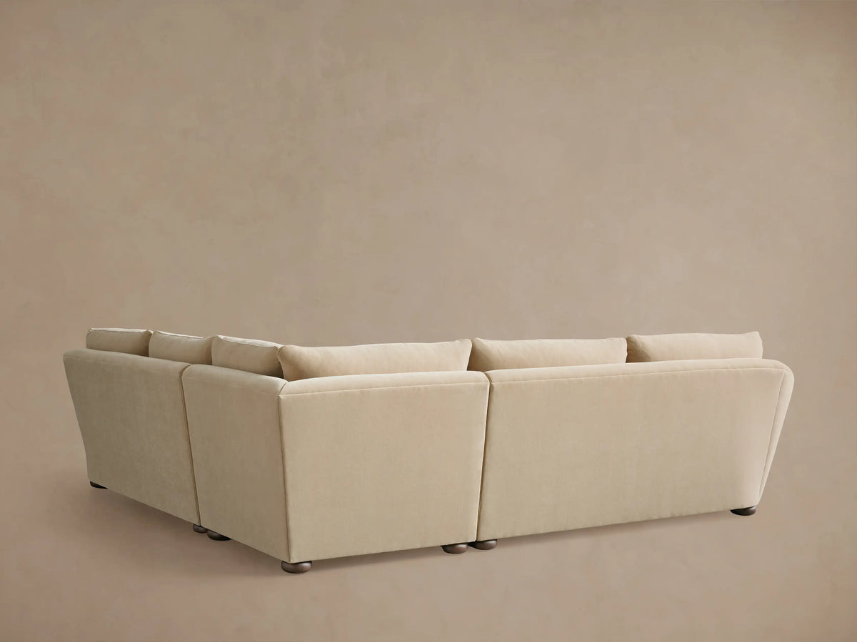 Alt text: Beige Archwood three-piece corner sectional with plush cushions and smooth upholstery, showing rounded armrest and soft fabric texture.