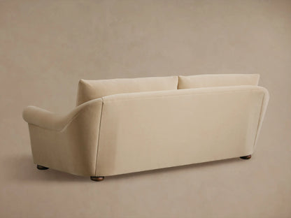 Close-up of a beige Archwood Sofa, showing the rolled armrest, seat cushions, and soft fabric.