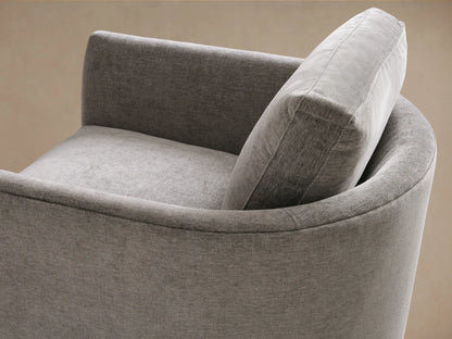 Bainbridge Chair in gray fabric, front view, features plush seat and back cushion. Wooden legs on a light wood floor, against beige wall.