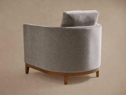 Bainbridge Chair in light gray fabric, featuring a curved back, plush seat, and armrest. Upholstery shows fine texture detail.
