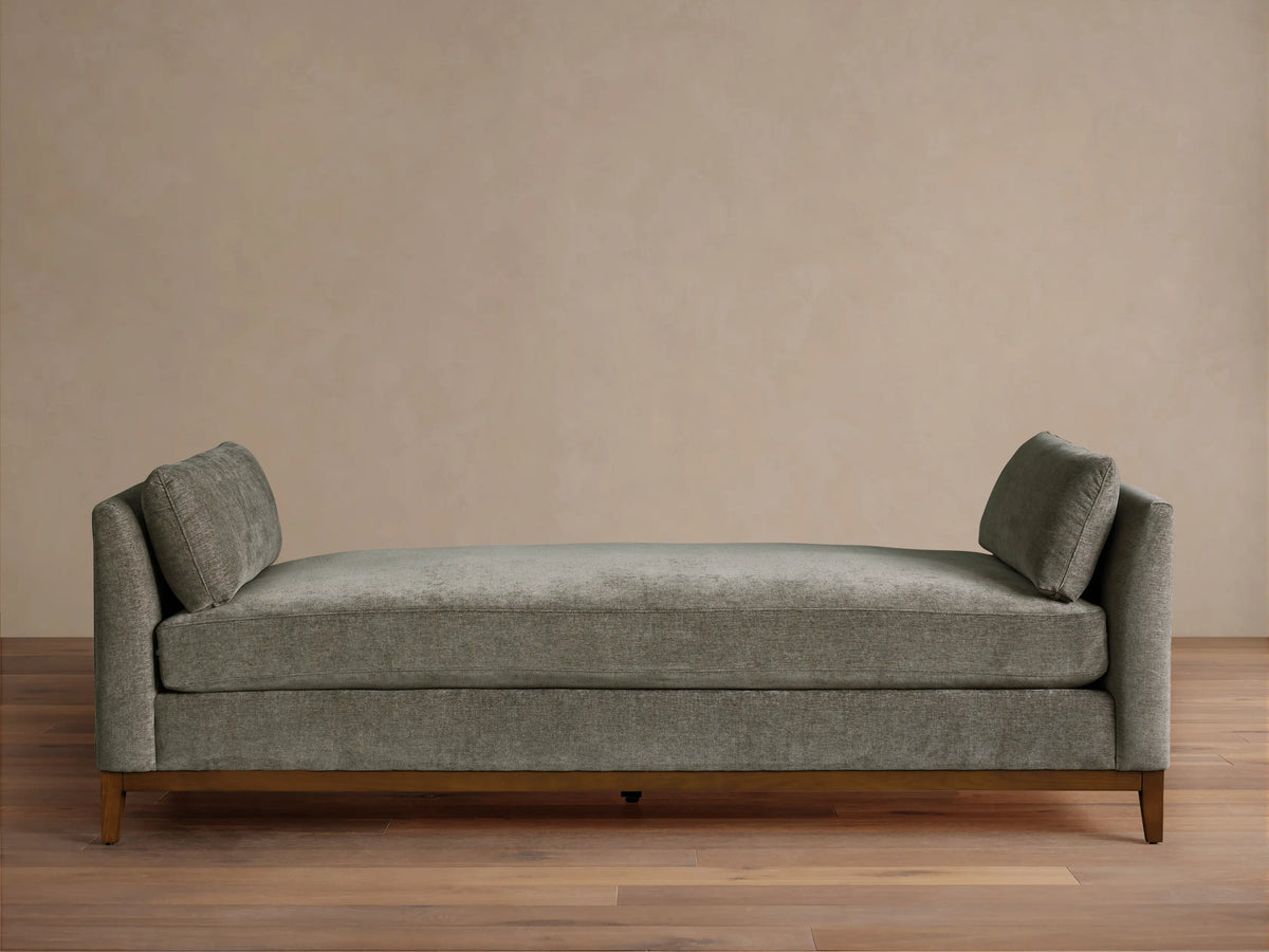 Bainbridge Daybed, gray-green textured fabric, two angled back cushions, dark wood base on wood floor.