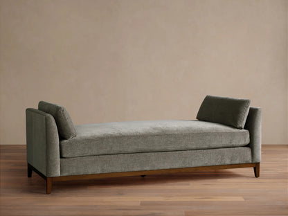 Bainbridge Daybed, gray-green textured fabric, two angled back cushions, dark wood base on wood floor.