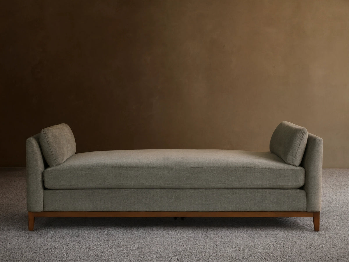 Bainbridge Daybed, gray-green textured fabric, two angled back cushions, dark wood base on wood floor.