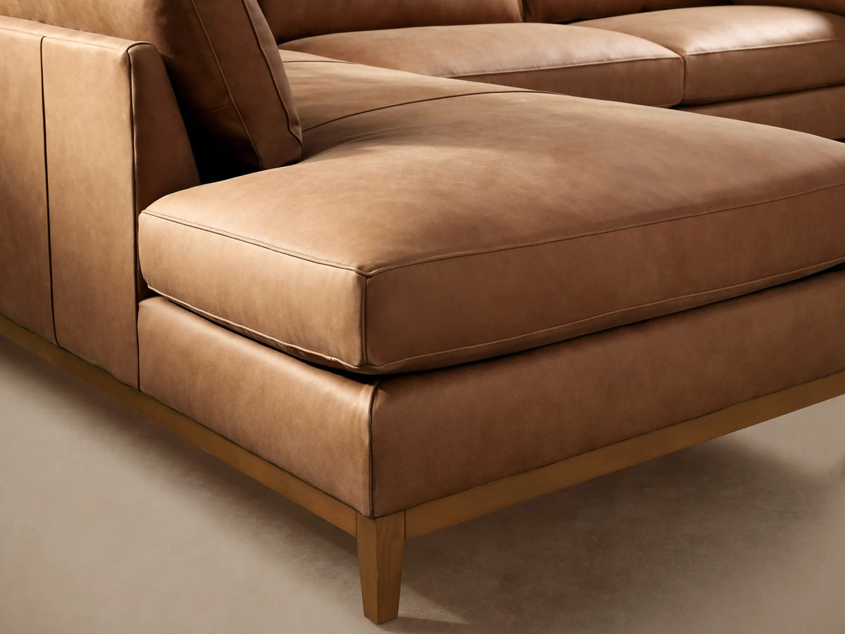 Bainbridge Two-Piece Bumper Sectional in camel leather, left-facing chaise, with light wood frame, on wood floor.