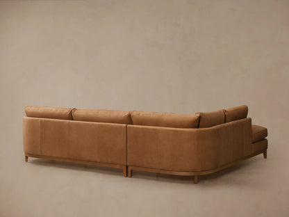 Close-up of Bainbridge Leather Two-Piece Bumper Sectional chaise. Light brown leather with visible stitching and a wooden base.