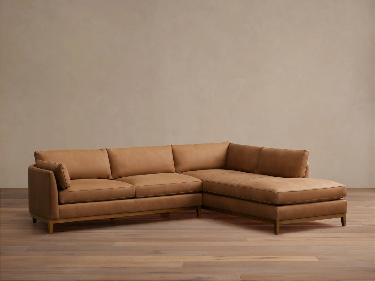 Bainbridge Two-Piece Bumper Sectional: L-shaped sofa in warm tan leather, with a right-side chaise, on a wood floor.