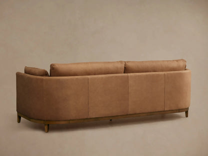 Close-up of the Bainbridge Leather Sofa, showing its curved armrest and back in rich, smooth camel-colored leather.