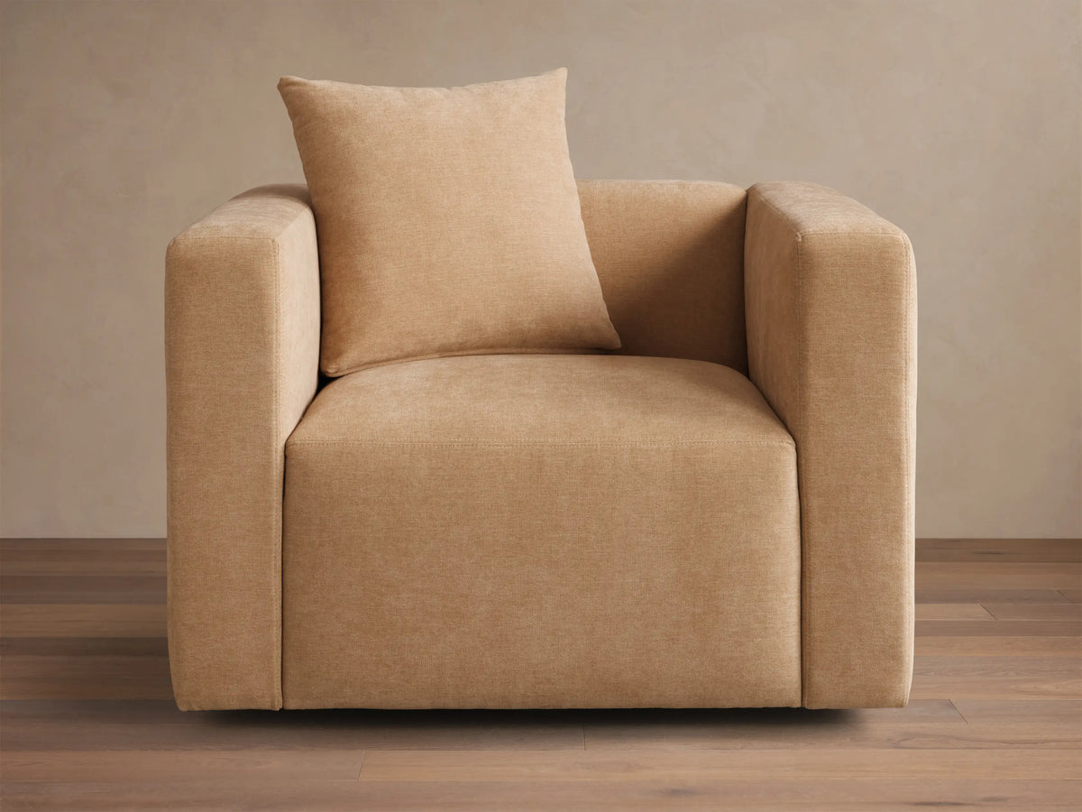 Front view of a beige Brady Swivel Chair, a cube-shaped armchair with a matching square pillow.