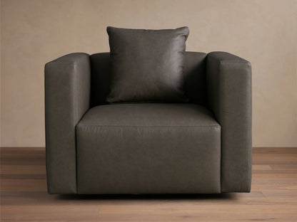Front-angled view of a Dark Gray Brady Leather Swivel Chair with square arms and a matching toss pillow.