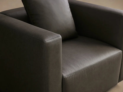 Front view of the Charcoal Brady Leather Swivel Chair, featuring a matching toss pillow and clean modern lines.