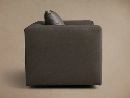 Rear-side view of the charcoal Brady Leather Swivel Chair™ with vertical stitch details and a matching toss pillow.