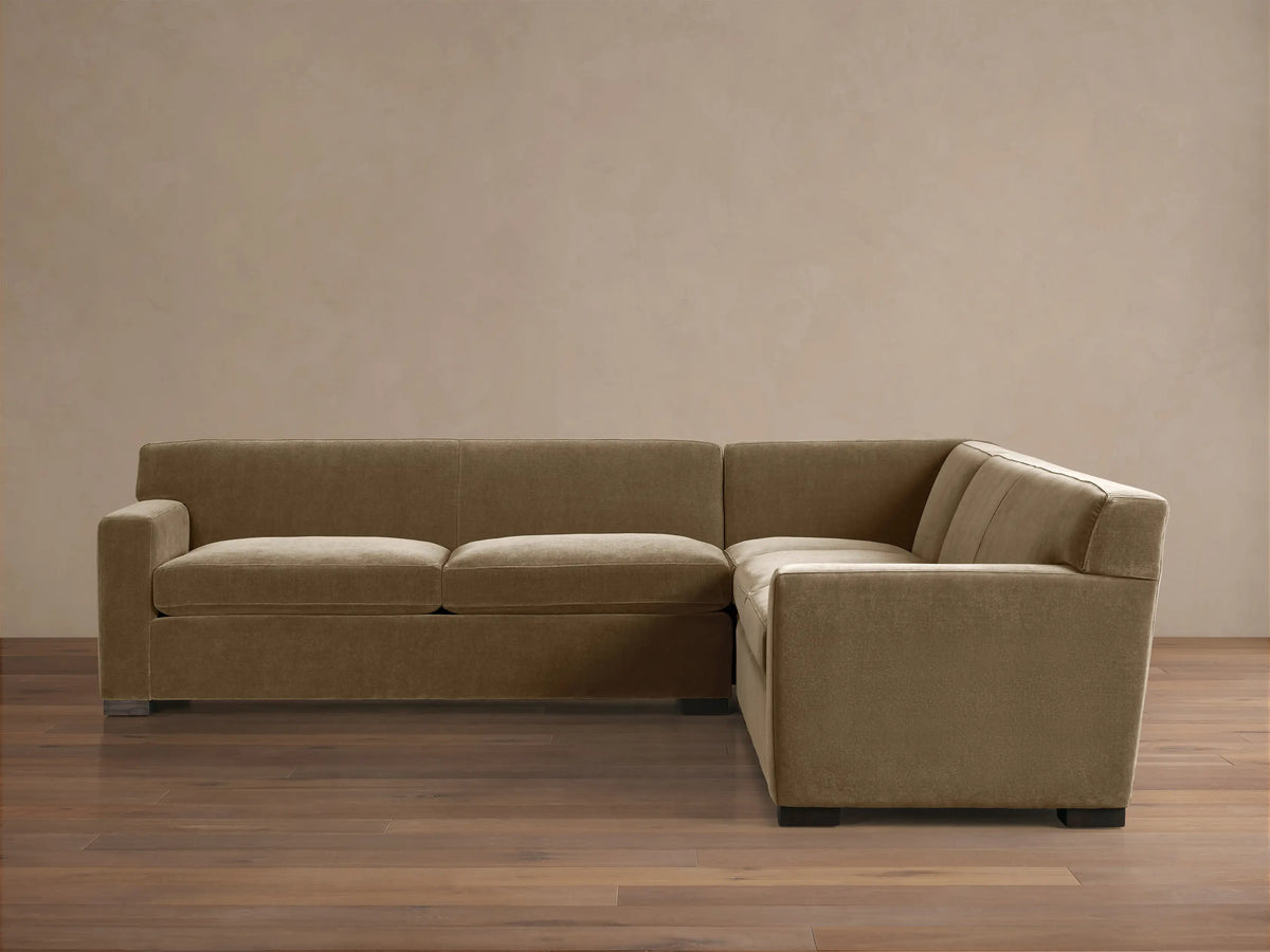 Bronte Three-Piece Corner Sectional in muted olive green fabric, forming an L-shape, on a wood floor against a beige wall.
