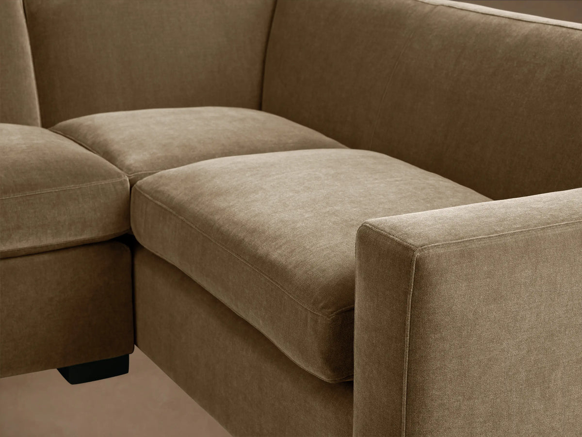 Bronte Two-Piece Sectional, L-shaped, in muted olive green fabric, with dark block legs on a hardwood floor.
