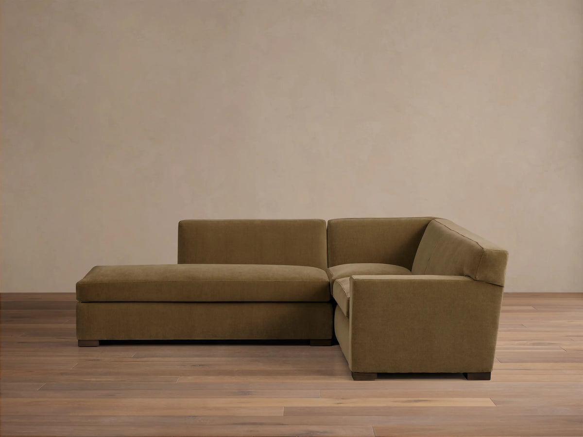 Front view of the olive green Bronte Two-Piece Bumper Chaise Sectional with square arms and dark block legs.